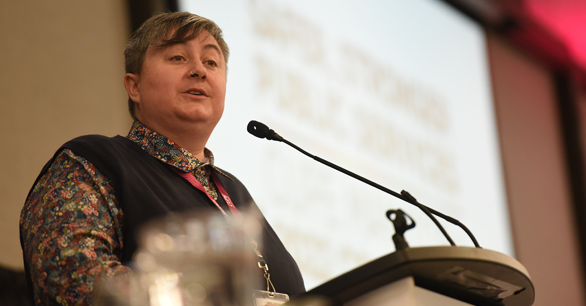 Gina McKay, President of CUPE Manitoba, addresses delegates while standing at a podium.