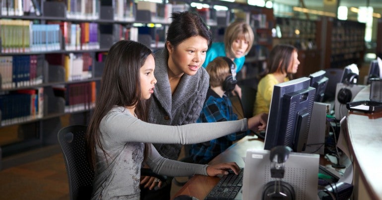 Librarian at a computer with young people