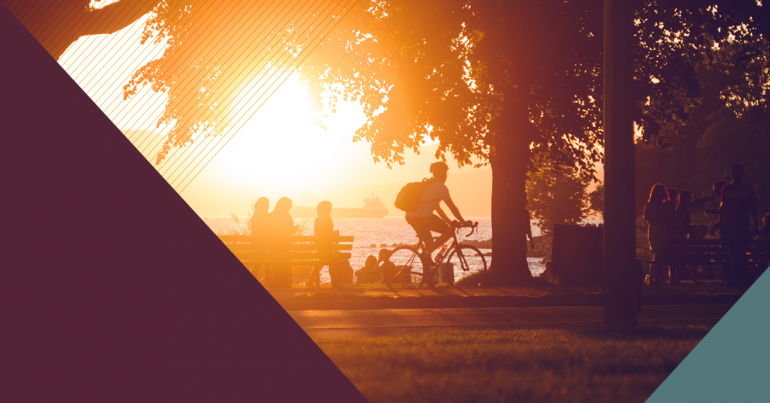 Cycliste et autres personnes rassemblées dans un parc près de la plage au coucher du soleil.