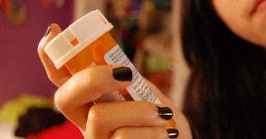 Close up of a hand holding a pill bottle//Gros plan d'une main tenant un flacon de pilules