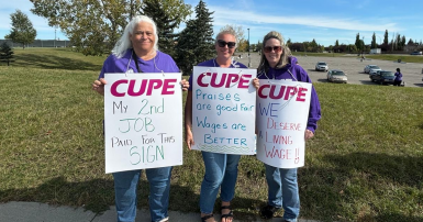 Three people standing with picket signs