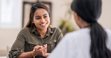A stressed-out woman is chatting with her mental health counselor. She is explaining her problems. She is staying positive with a smile.