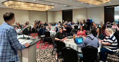 Speaker at the front of a room full of people