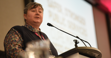 Gina McKay, President of CUPE Manitoba, addresses delegates while standing at a podium.
