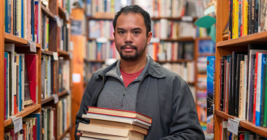 Library worker looks serious and is holding a stack of books to put away.