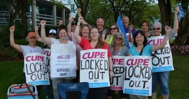 Pacific Blue Cross workers wearing signs that say lockout