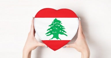 Les mains d'une femme qui tient une boîte en forme de coeur avec le drapeau du liban