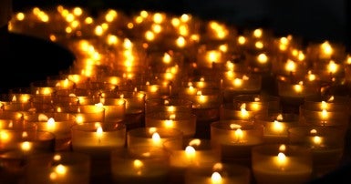 Many lit candles against a black background