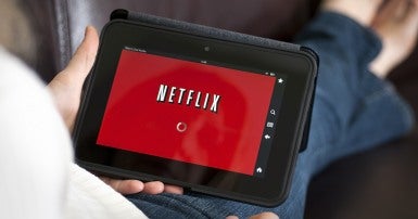 Picture shows an electronic table with a red screen with white block letters that say NETFLIX