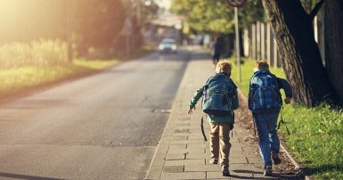 deux écoliers qui courent le long d'un trottoir