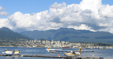 Float planes parked on water in front of a city and mountains
