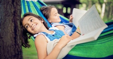 Two children reading in a hammock