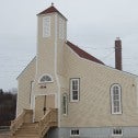 Beige coloured chruch with a red roof, a bell tower and arched windows