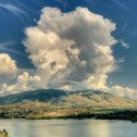 Image of lake surrounded by mountains in summer with dramatic cloud 