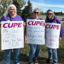 Three people standing with picket signs