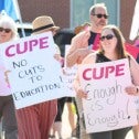 People holding signs protesting cuts to education
