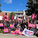 Workers pose for photo with flags and picket signs