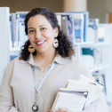 A woman poses in the library for her business headshot.