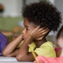 Young girl with her head in her hands at a school desk