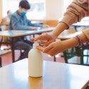 Student using hand sanitizer in classroom with other students