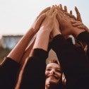 Soft focus image of a small group of women with their arms raised, touching hands