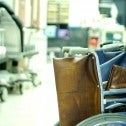 Photo of a hospital room with empty wheelchairs in the foreground and empty gurneys in the background.