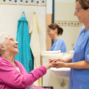 Long term care worker holding hand of elderly woman in wheelchair