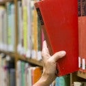Hand taking a book from a library shelf
