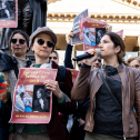 Group of women holding signs and talking on a microphone at a protest