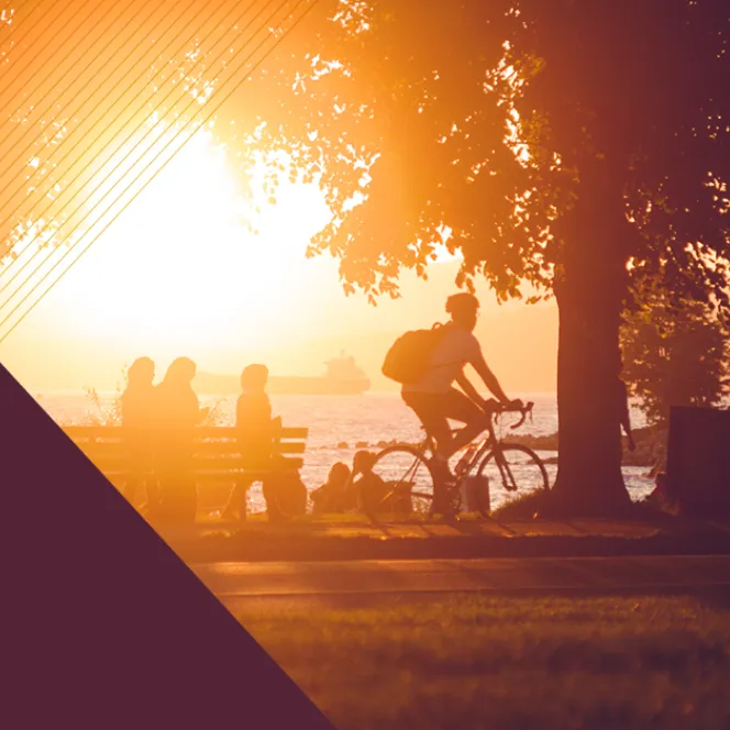 Cycliste et autres personnes rassemblées dans un parc près de la plage au coucher du soleil.