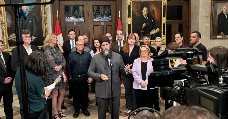 People standing in front of cameras at a press conference 