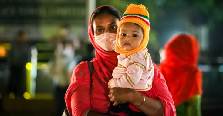 A garment worker on the way out of work with her child in Dhaka, Bangladesh.