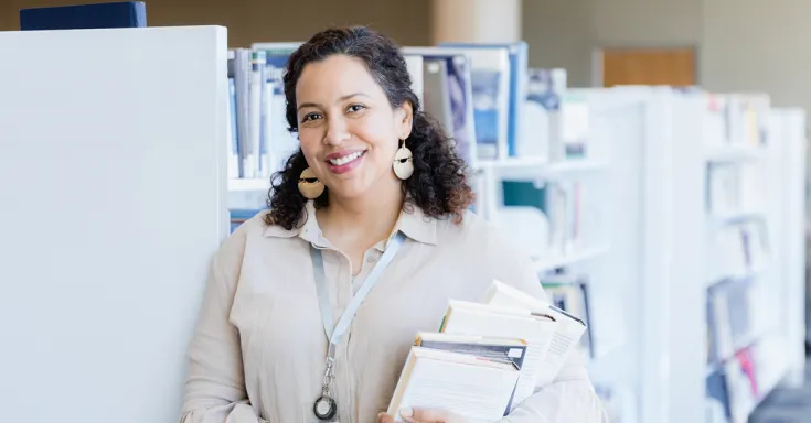 A woman poses in the library for her business headshot.