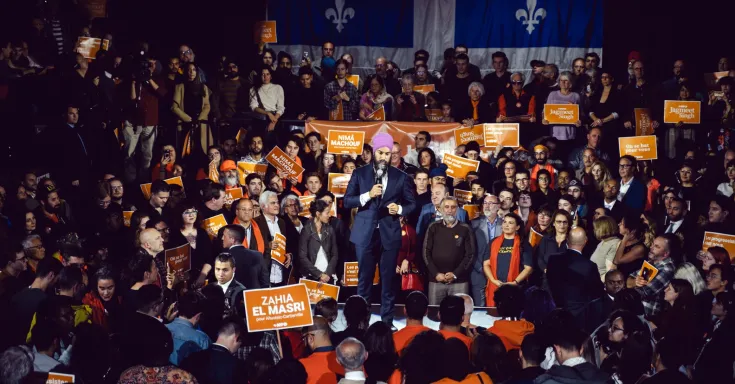 NDP Leader Jagmeet Singh in the centre of a large rally with a Quebec flag as a backdrop
