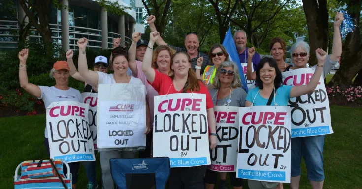Pacific Blue Cross workers wearing signs that say lockout