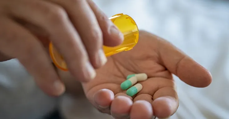 Person emptying a bottle of prescription medicine into their hand