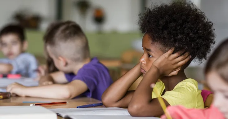 Young girl with her head in her hands at a school desk