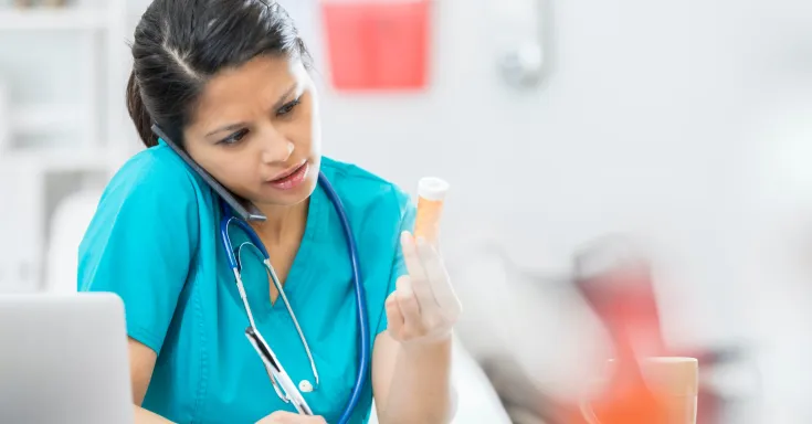 Nurse on phone with medication in hand