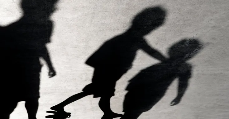 Shadows of three children on a grey concrete surface with cracks