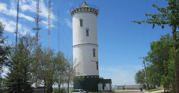 Photo of tall white water tower against a blue sky