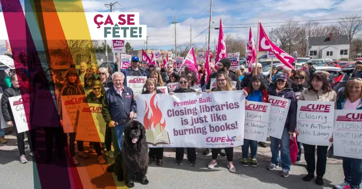 Groupe de manifestants tenant des pancartes pro-bibliothèque, et un gros chien noir