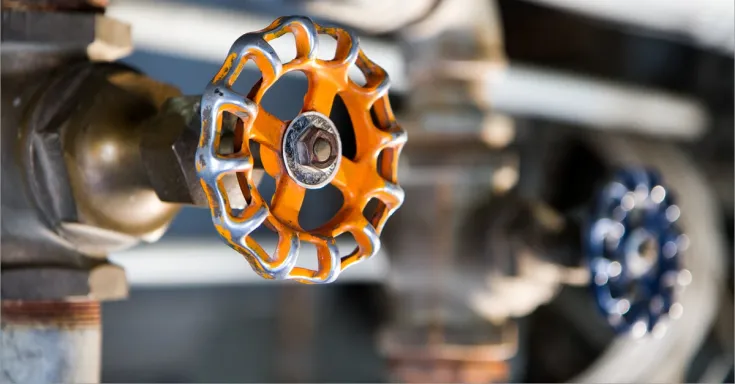 Close up of orange tap on copper water pipe