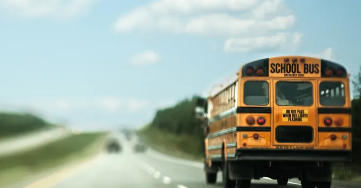 A school bus traveling down a highway. Photographed with a tilt-shift lens.