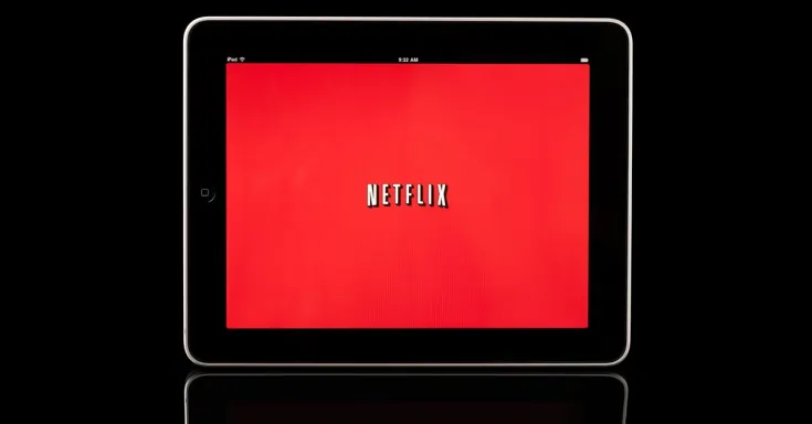 Picture shows an electronic table with a red screen with white block letters that say NETFLIX