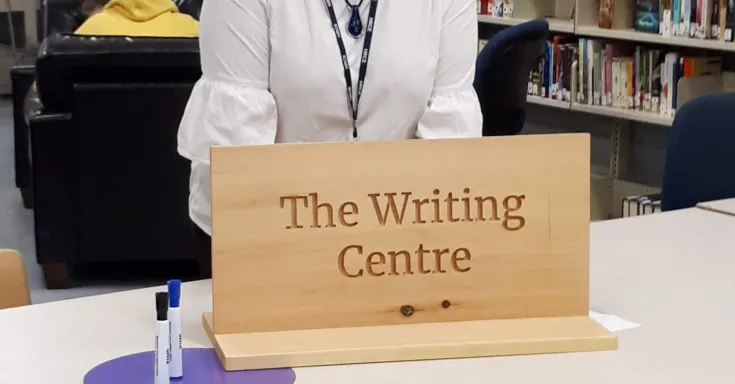woman standing behind a table at a library 