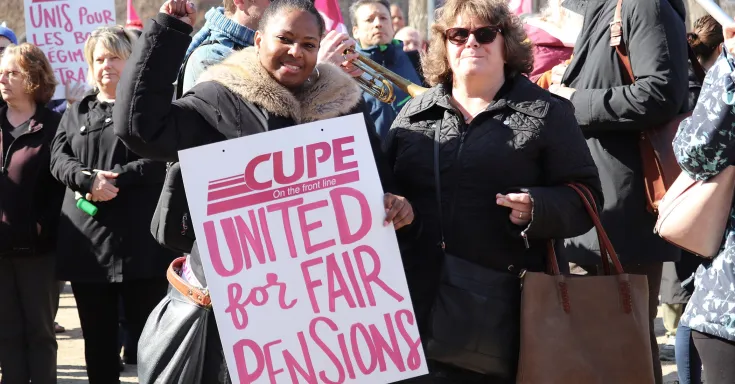 Two women at a CUPE 1975 rally, one holds a sign that says United for Fair Pensions